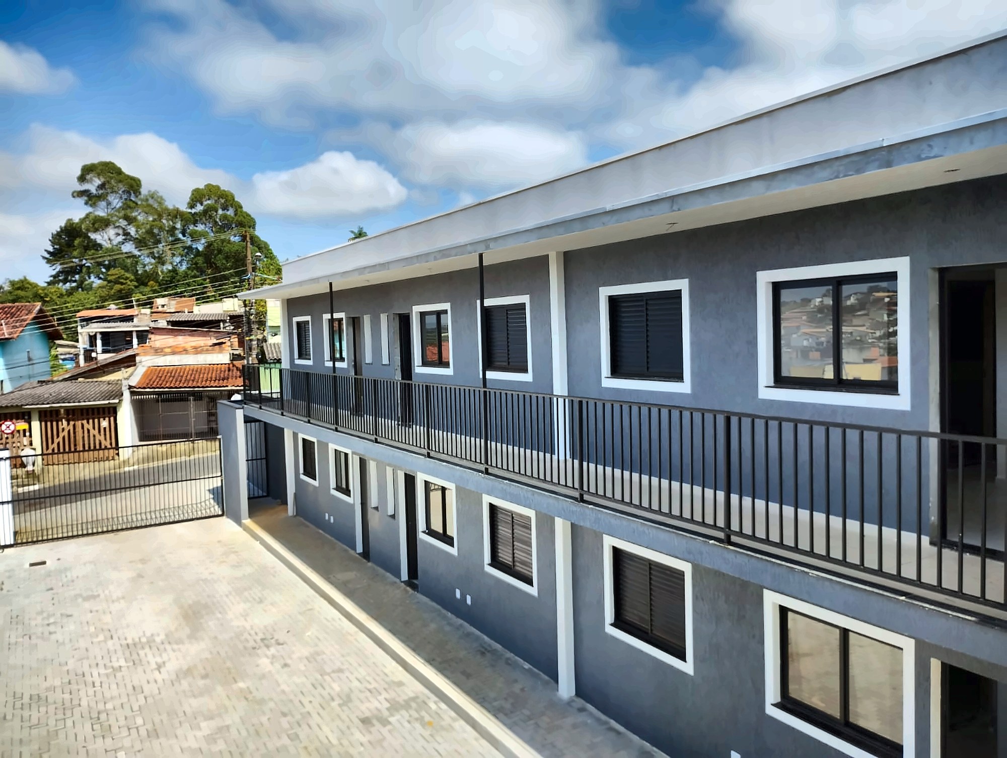 Conjunto residencial de dois pavimentos com fachada texturizada em cinza e esquadrias pretas