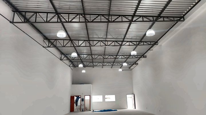Interior de galpão com tesouras metálicas e luminárias
