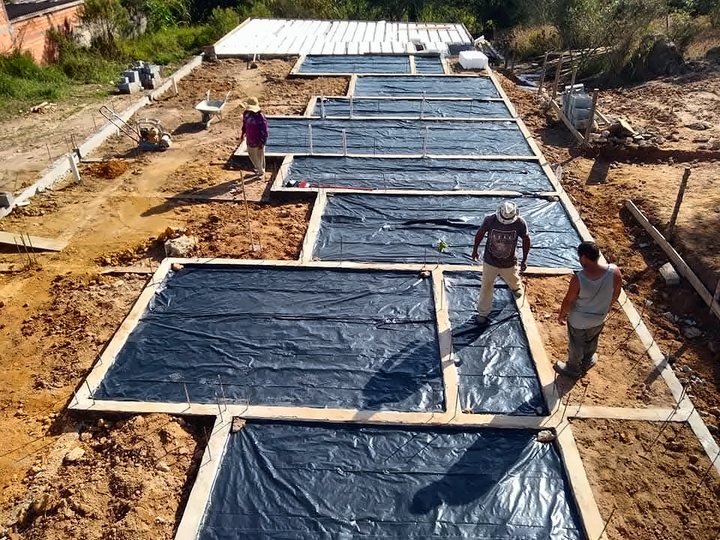 Equipe preparando radier com lona plástica para concretagem