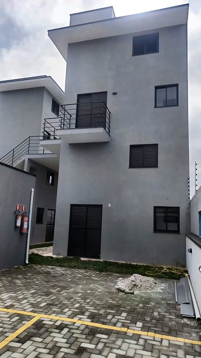 Edifício residencial de três andares com sacada e piso intertravado